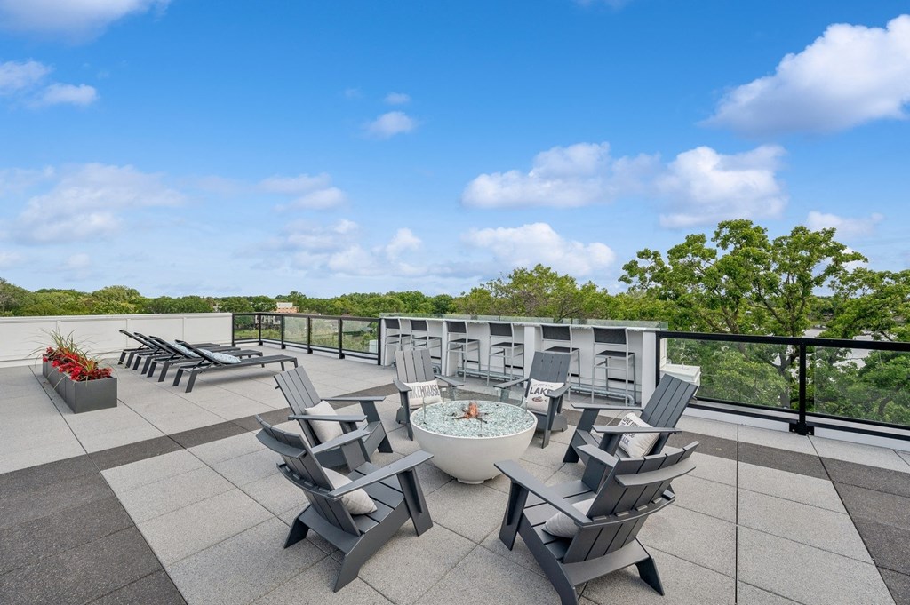 the terrace of a building with chairs and a fire pit