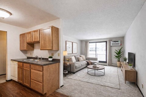 A modern kitchen with wooden cabinets and a grey sofa in the living room.