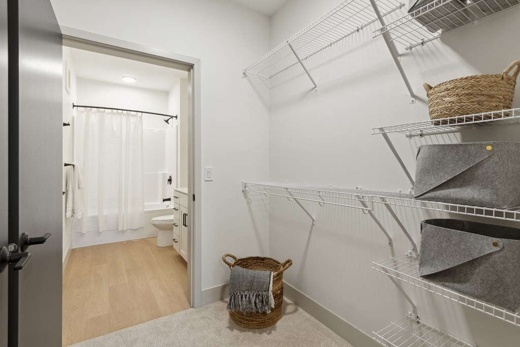 a walk in closet with shelves and baskets and a door to a bathroom