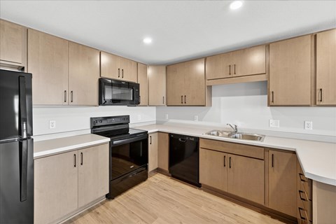 A kitchen with wooden cabinets and black appliances.