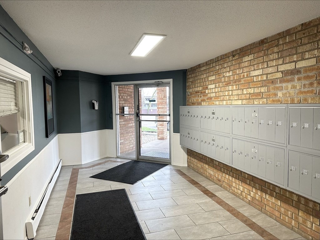 the locker room at the clubhouse has a brick wall and white lockers