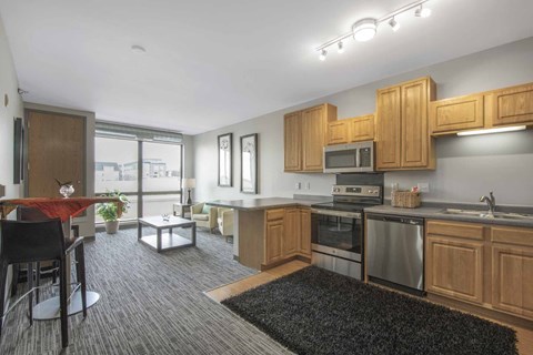a kitchen and living room with wooden cabinets and stainless steel appliances