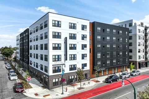 A street view of a residential area with modern buildings and cars parked on the side of the road.