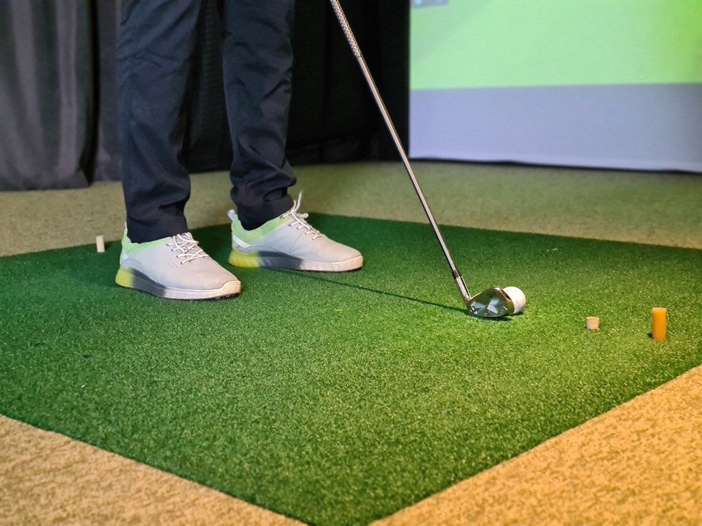 a golfer standing next to a golf ball on a putting green