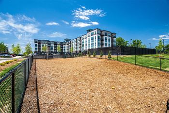 a fenced in dog park with apartments in the background