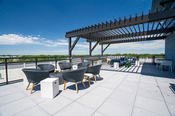 a rooftop patio with chairs and tables and a pergola