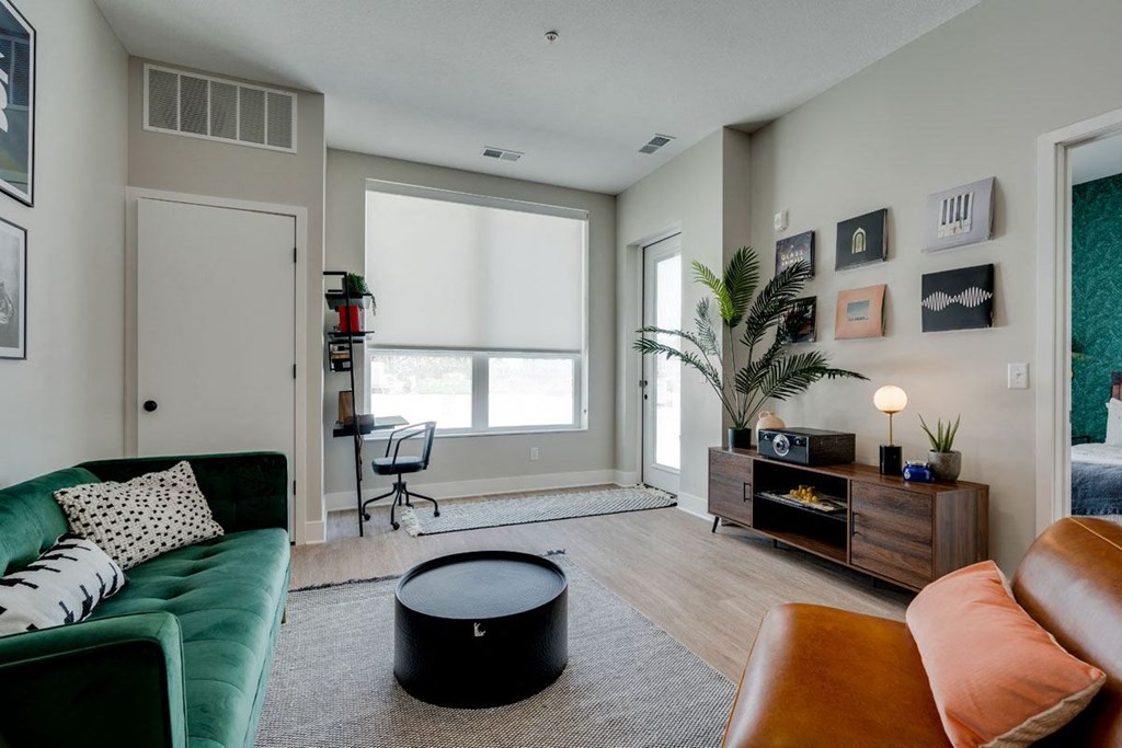 a living room with a green couch and a large window