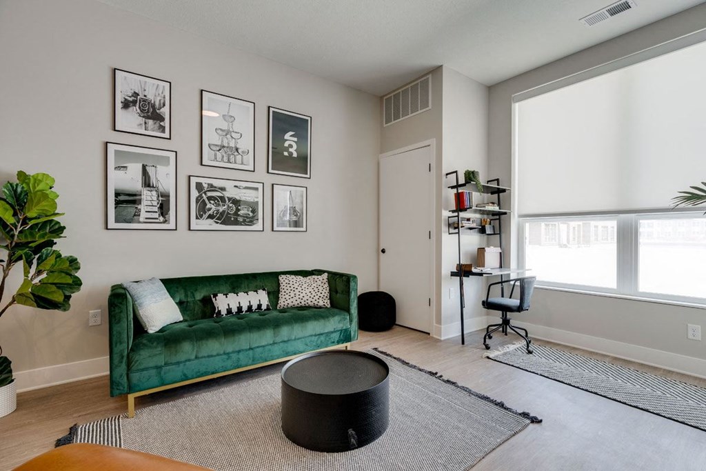 a living room with a green couch and pictures on the wall
