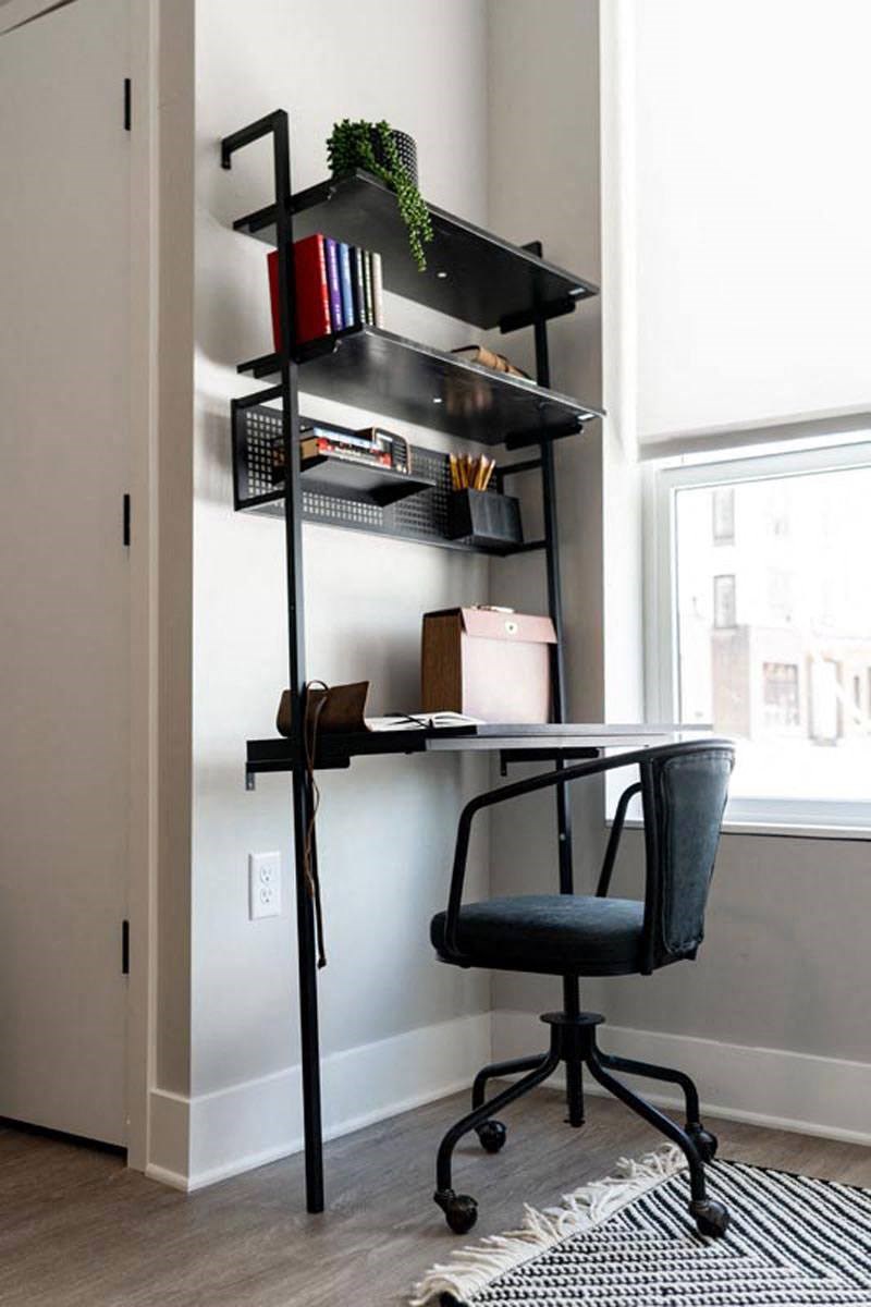 a desk with a chair and some shelves on a wall