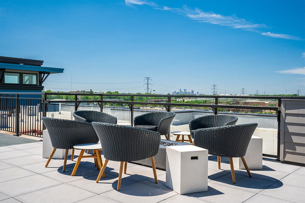 a rooftop terrace with chairs and tables on a sunny day