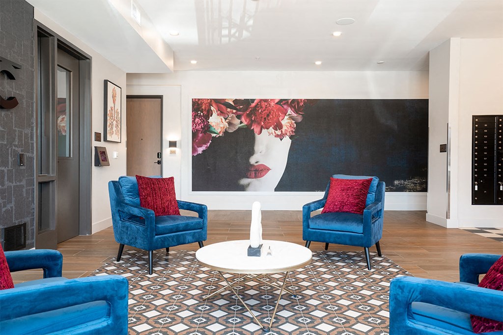 a living room with blue chairs and a large painting