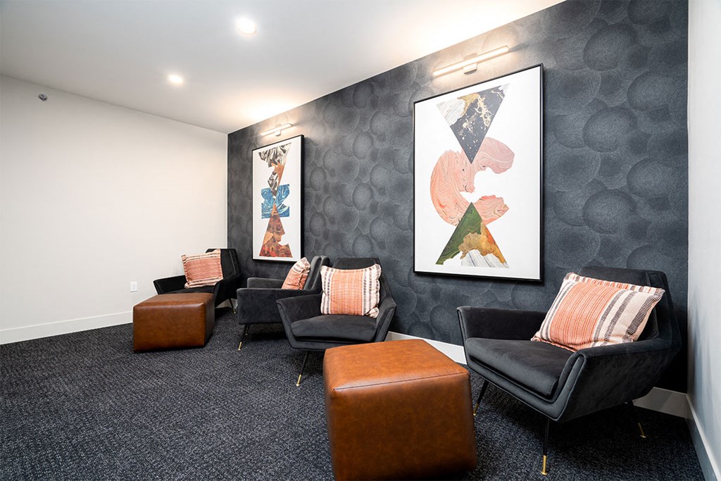 a lounge area with chairs and paintings on the wall