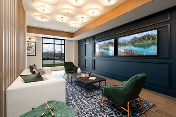 a living room with a white couch and green chairs and a television on the wall
