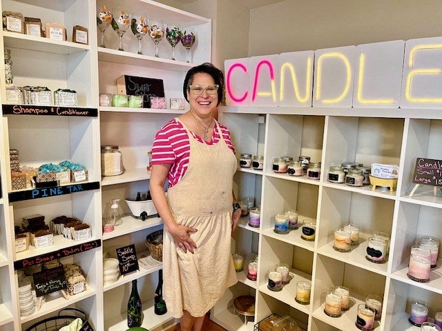 a woman standing in front of a shelf of candles