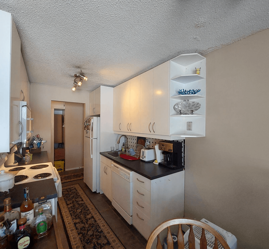 a small kitchen with white cabinets and a wooden table
