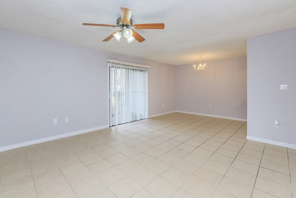 an empty living room with a ceiling fan and a tiled floor