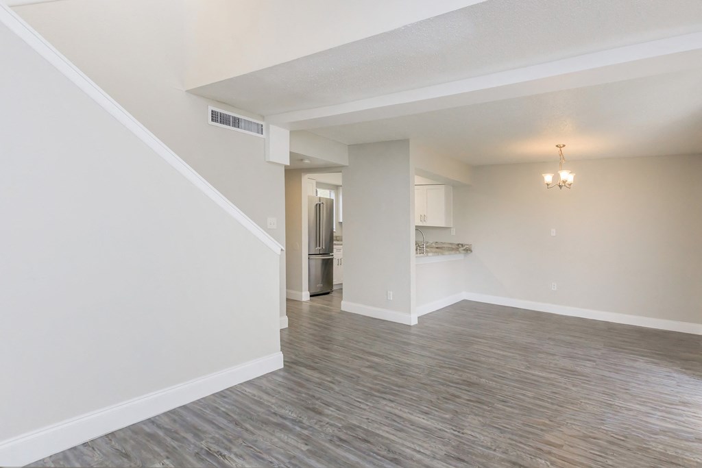 the living room and kitchen of an empty apartment with white walls and wood flooring