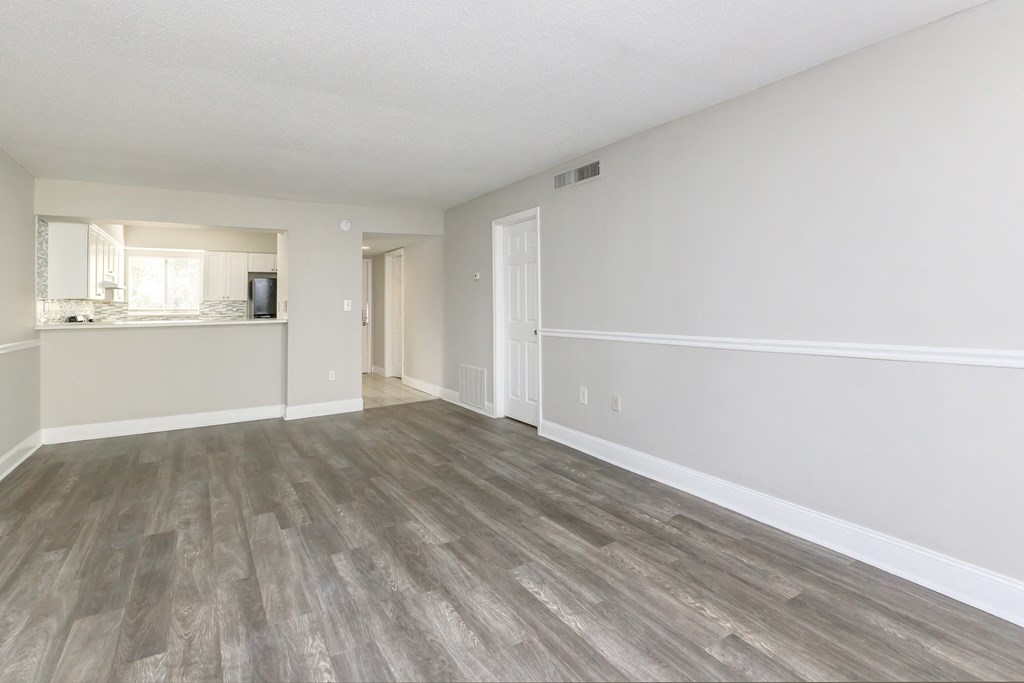 the spacious living room and kitchen of an apartment