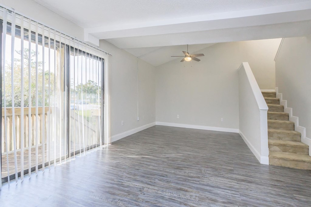 an empty living room with a staircase and a ceiling fan