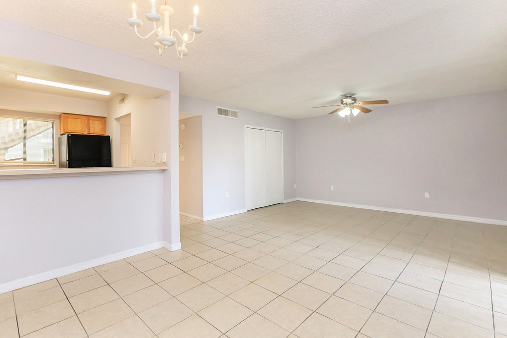 the living room and dining room of an empty home with a ceiling fan