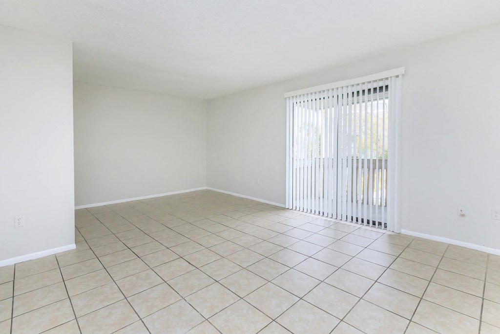 an empty living room with a sliding glass door and tiled floor