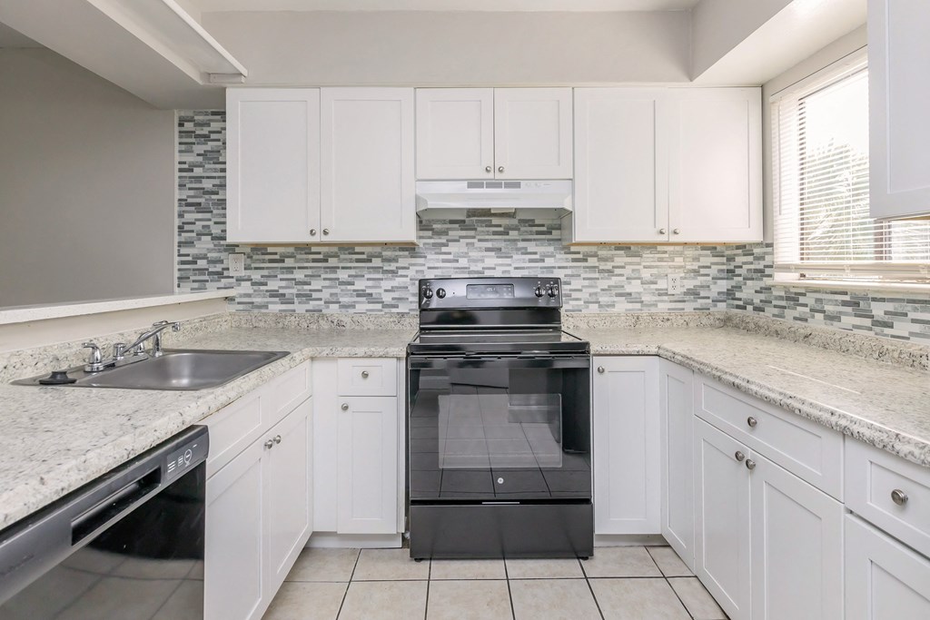 a kitchen with white cabinets and a stove and a sink