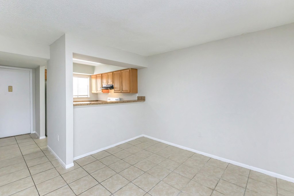 the living room and kitchen of an empty house with a tiled floor