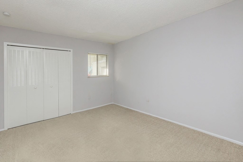 an empty bedroom with a closet and a window