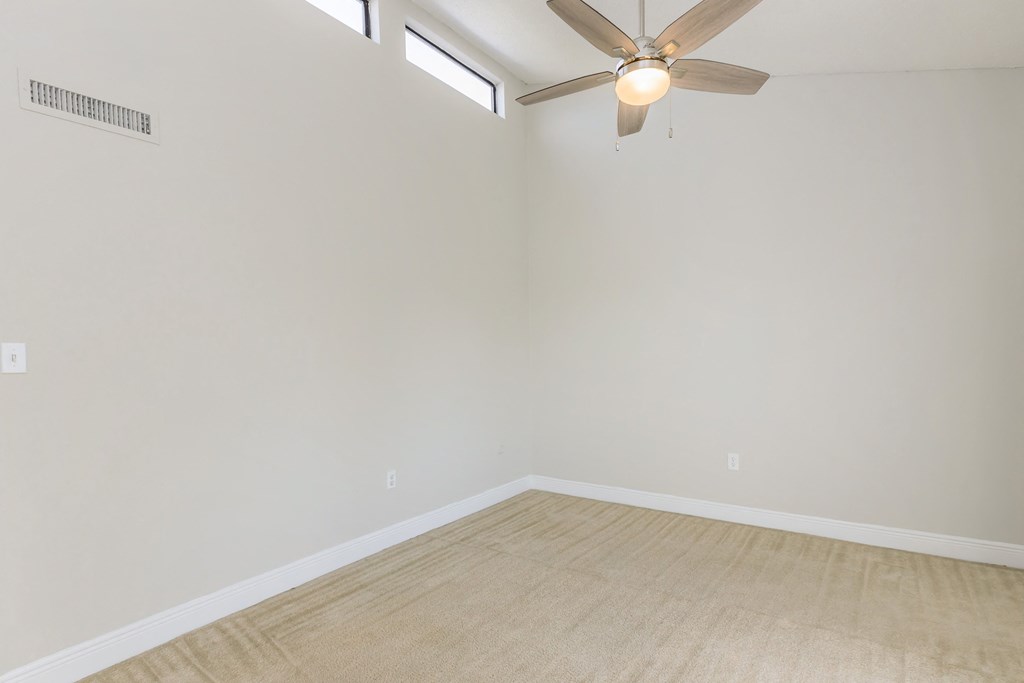 an empty room with a ceiling fan and white walls