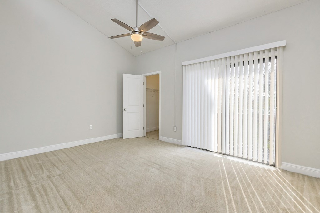 an empty living room with blinds and a ceiling fan