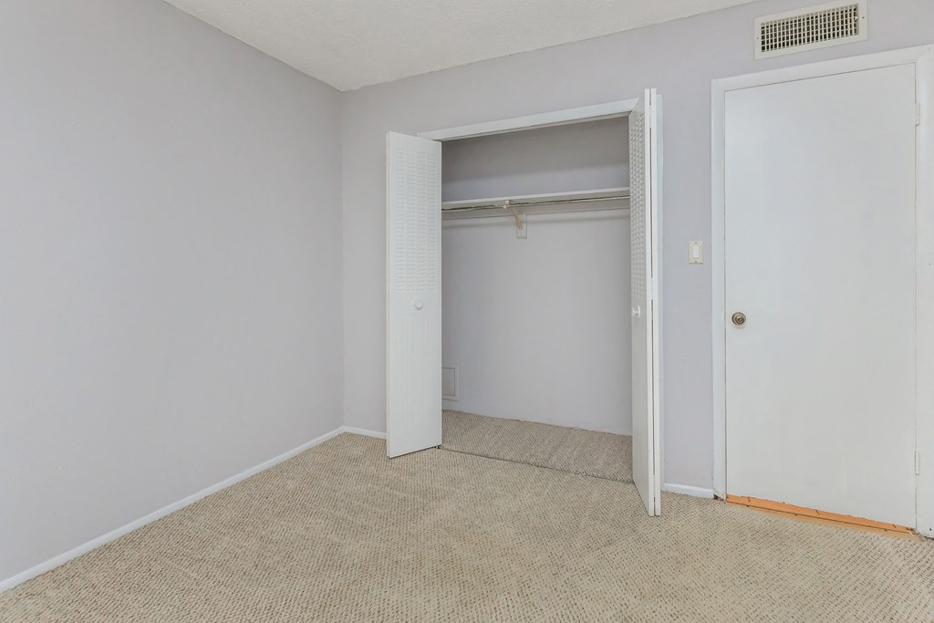 an empty bedroom with an open closet door