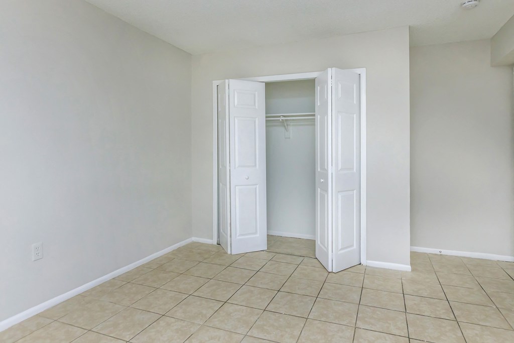 an empty bedroom with a closet and a tiled floor