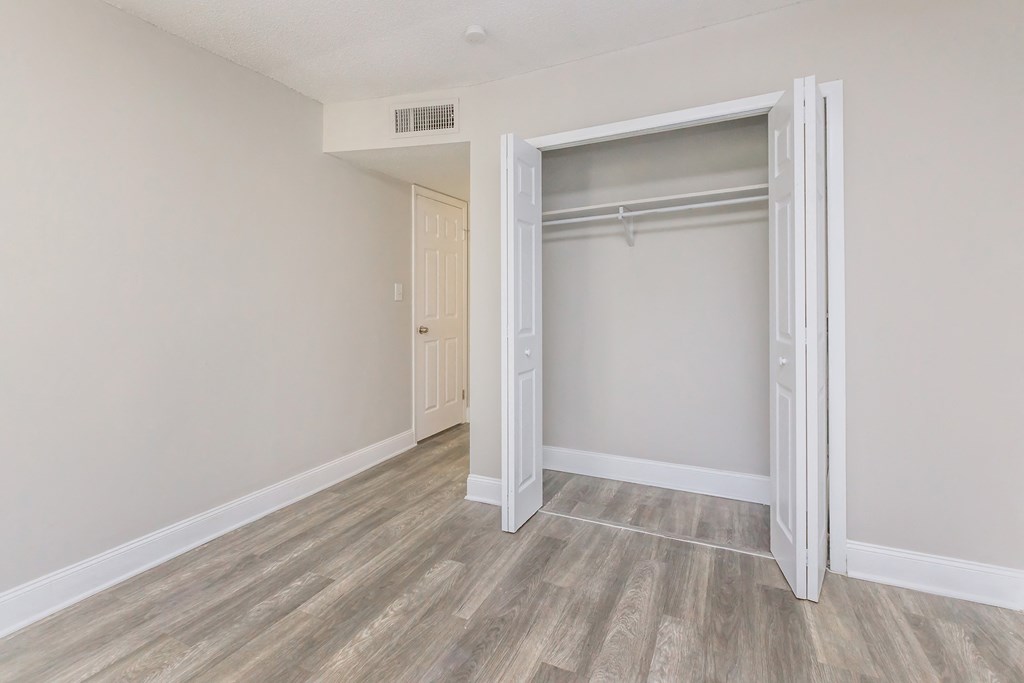 an empty bedroom with a closet with a sliding door