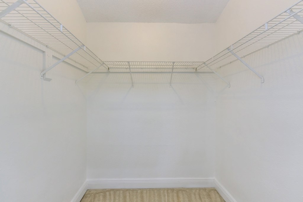 an empty white room with a wire rack on the wall