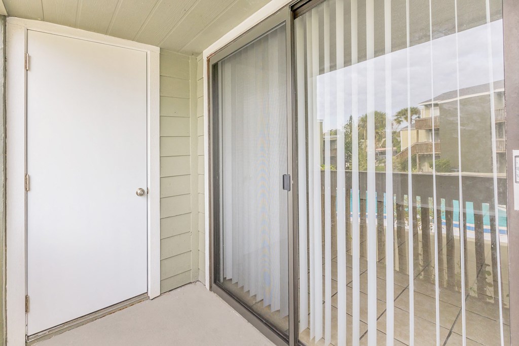 a sliding glass door leading to a balcony with a pool