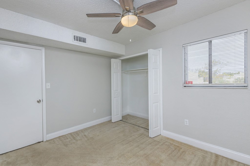 a bedroom with a ceiling fan and a door to a closet