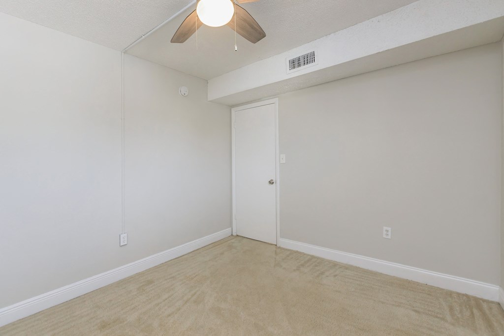 an empty room with a ceiling fan in the corner