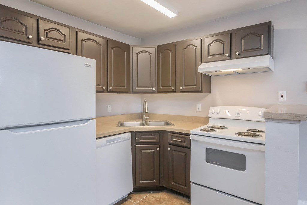 an empty kitchen with white appliances and brown cabinets