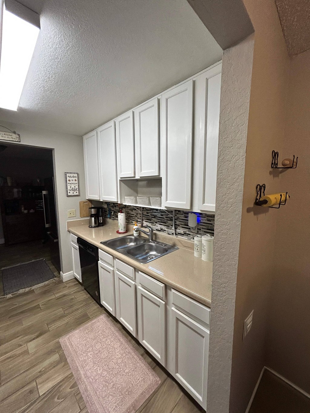 A kitchen with white cabinets and a pink rug on the floor.
