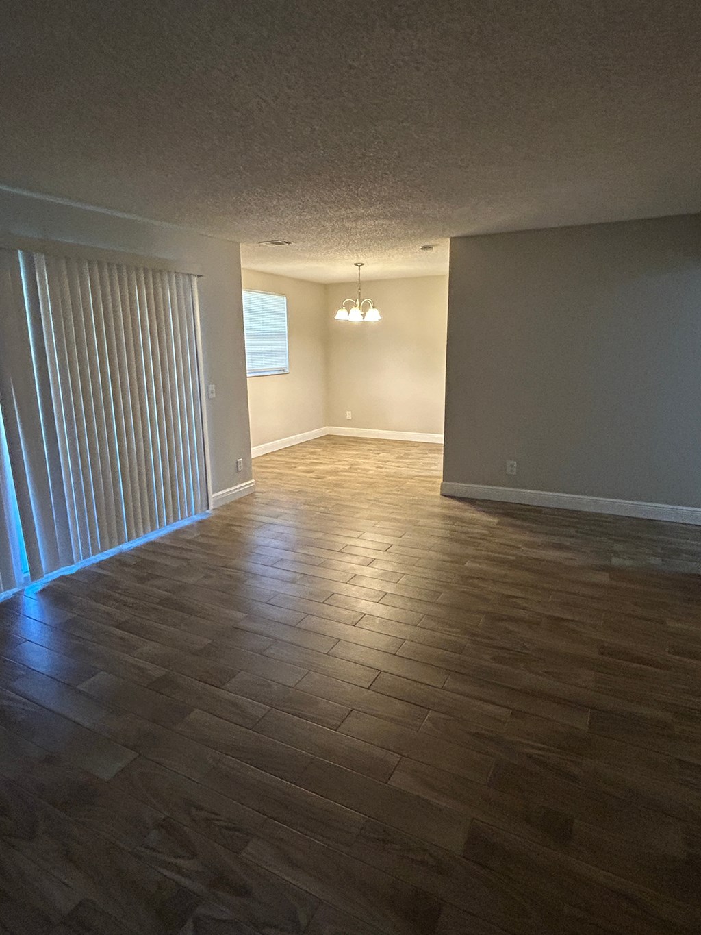 A room with wooden flooring and a window with blinds.
