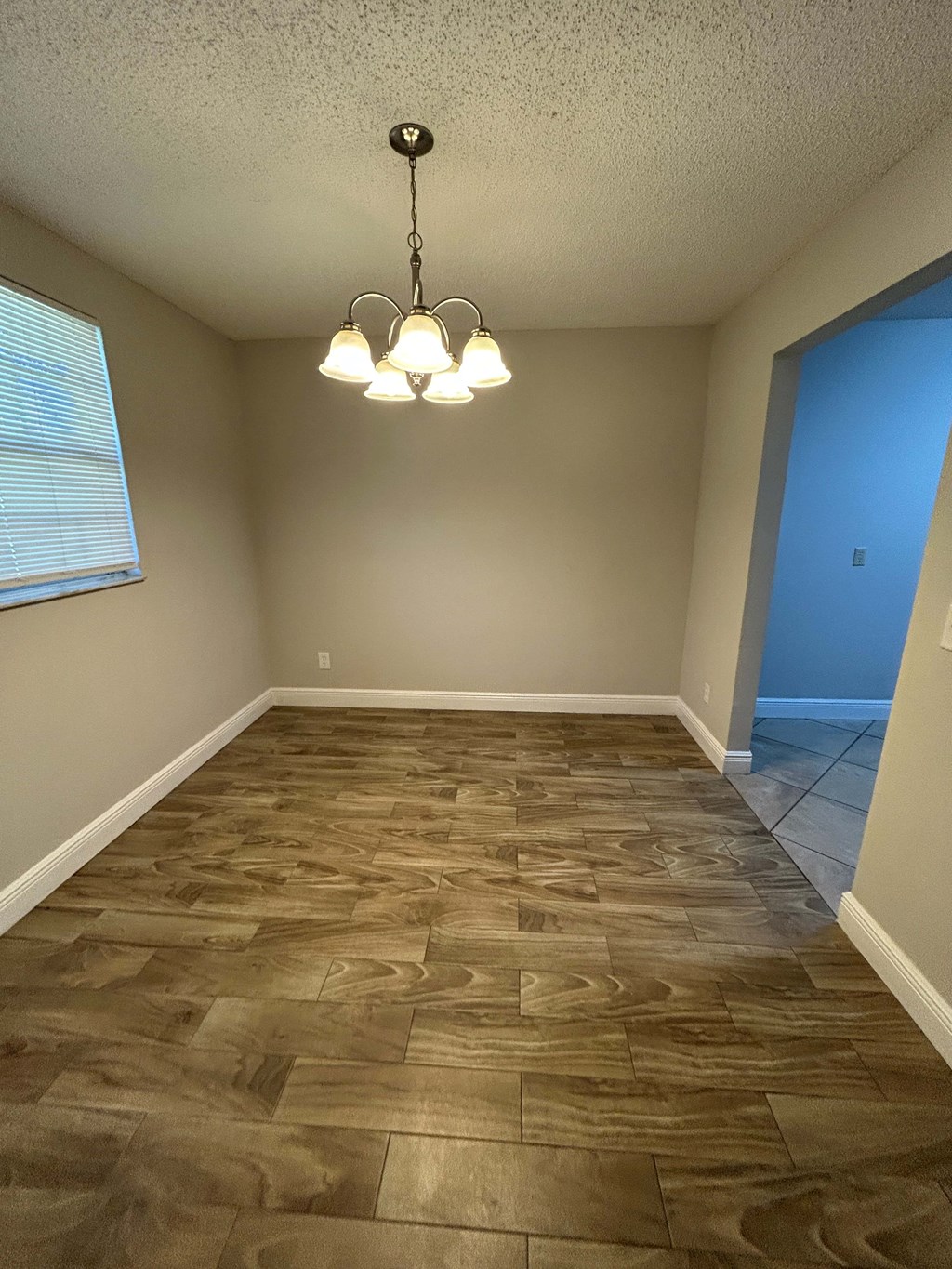 A room with wooden flooring and a chandelier.