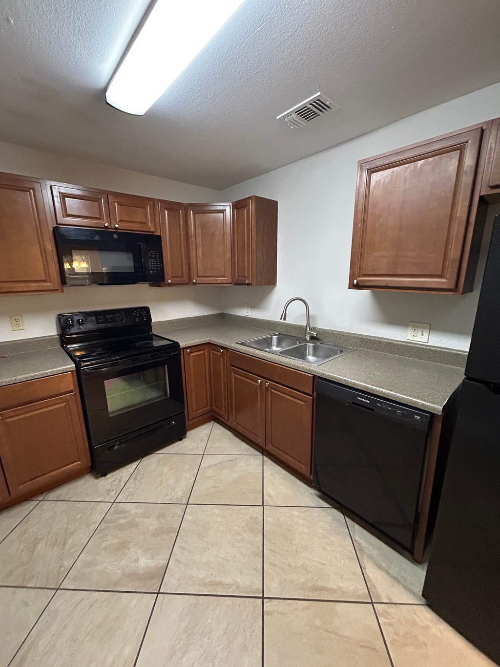 A kitchen with black appliances and brown cabinets.