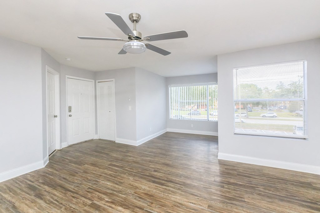 an empty living room with a ceiling fan and a window