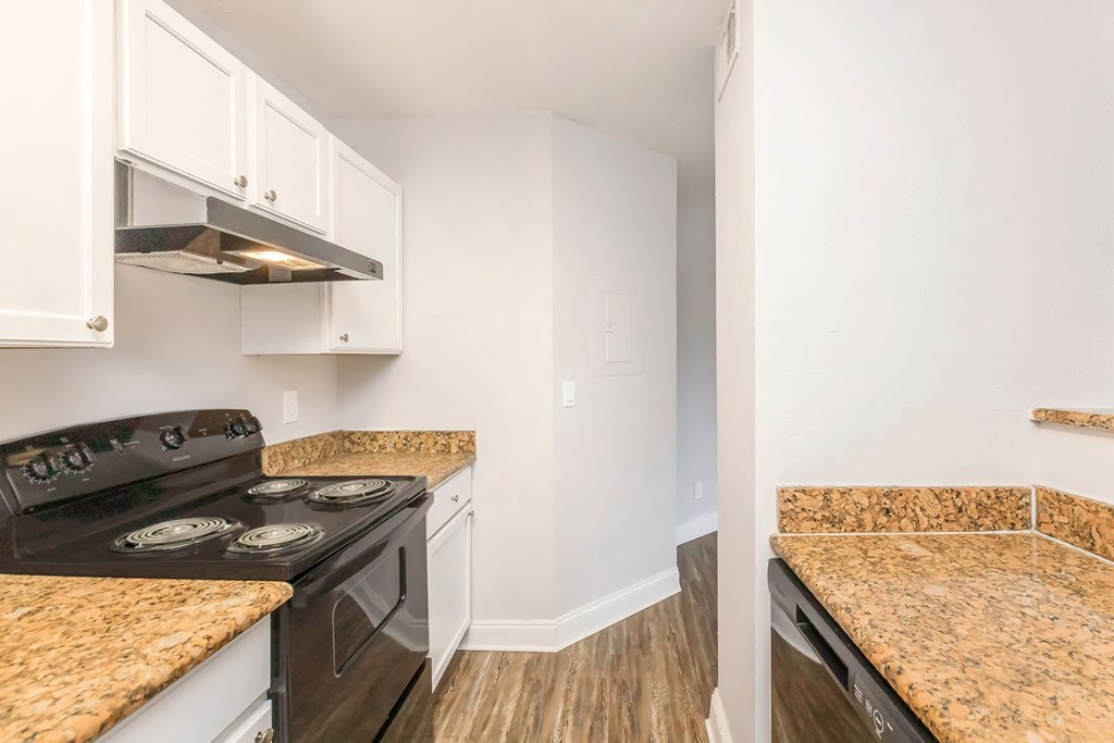 a kitchen with white cabinets and black appliances and granite counter tops