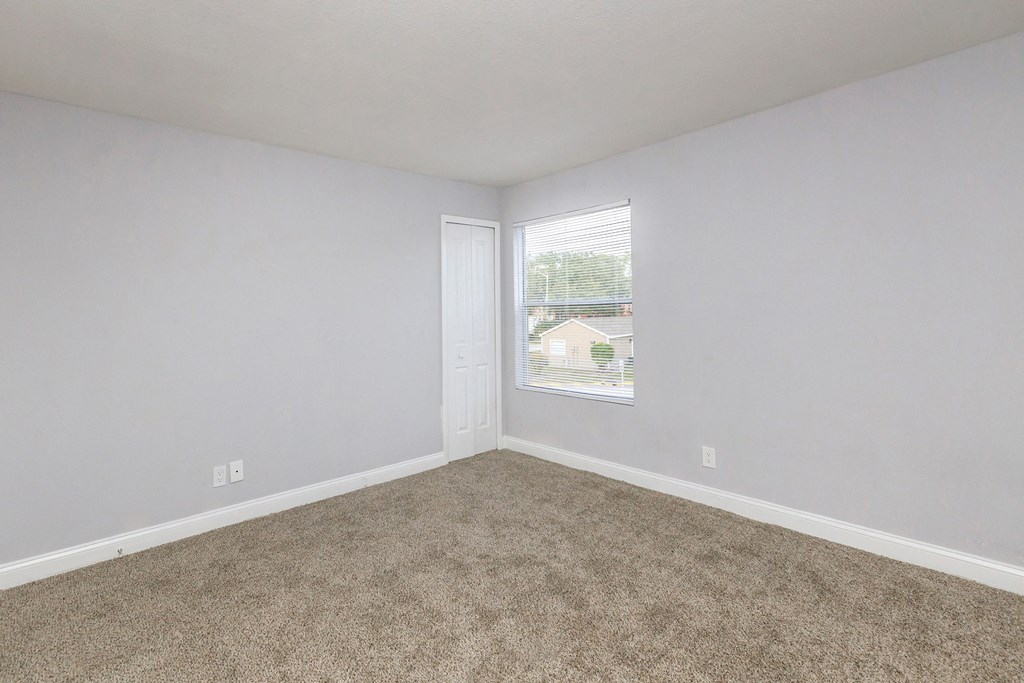 an empty room with carpet and a window