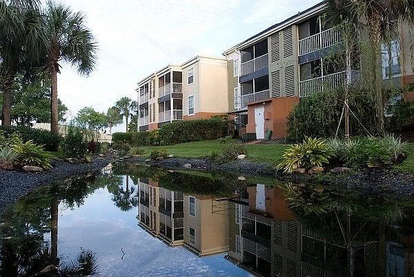 A building with a green roof is reflected in the water.