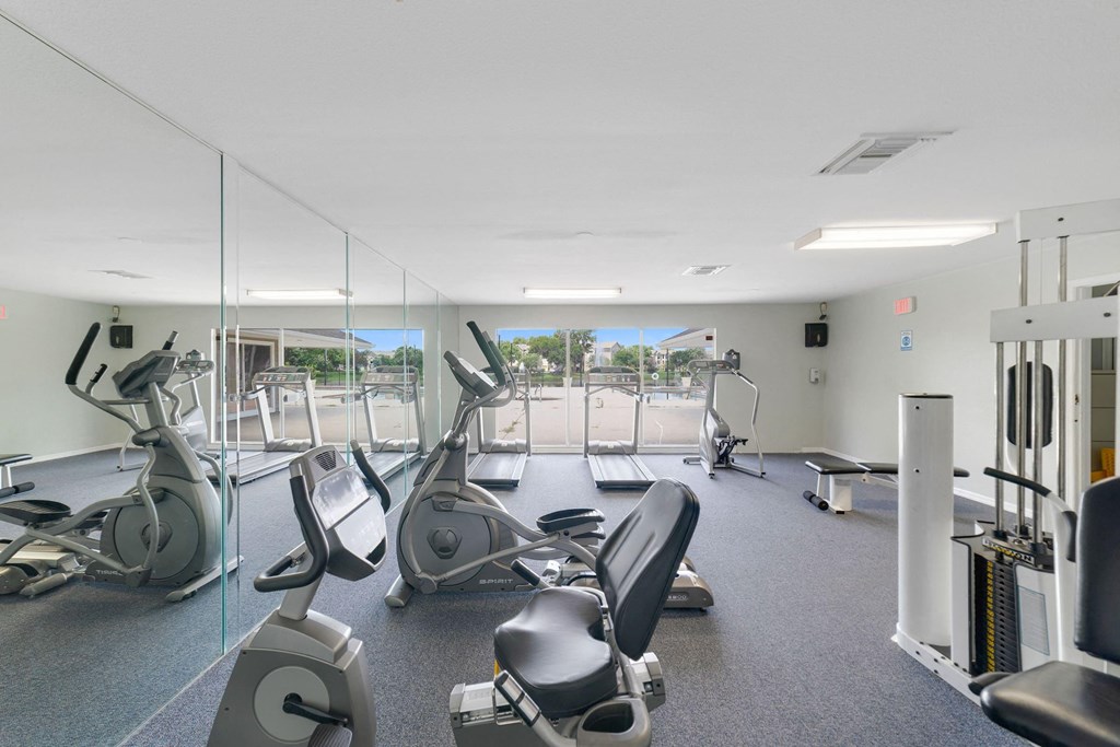 a gym with cardio equipment and mirrors in a building