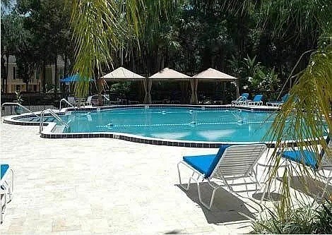 A pool surrounded by trees and chairs.