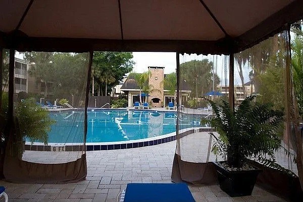 A pool is surrounded by a patio and a canopy.
