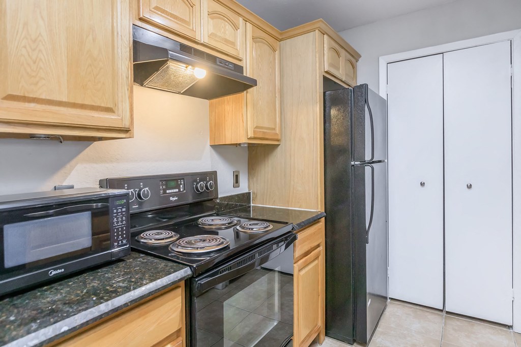 a kitchen with wood cabinets and black appliances and a refrigerator